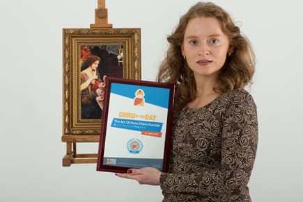 Anna Maria Karolak holding her framed Guru of the Day certificate for The Art Of Anna Maria Karolak